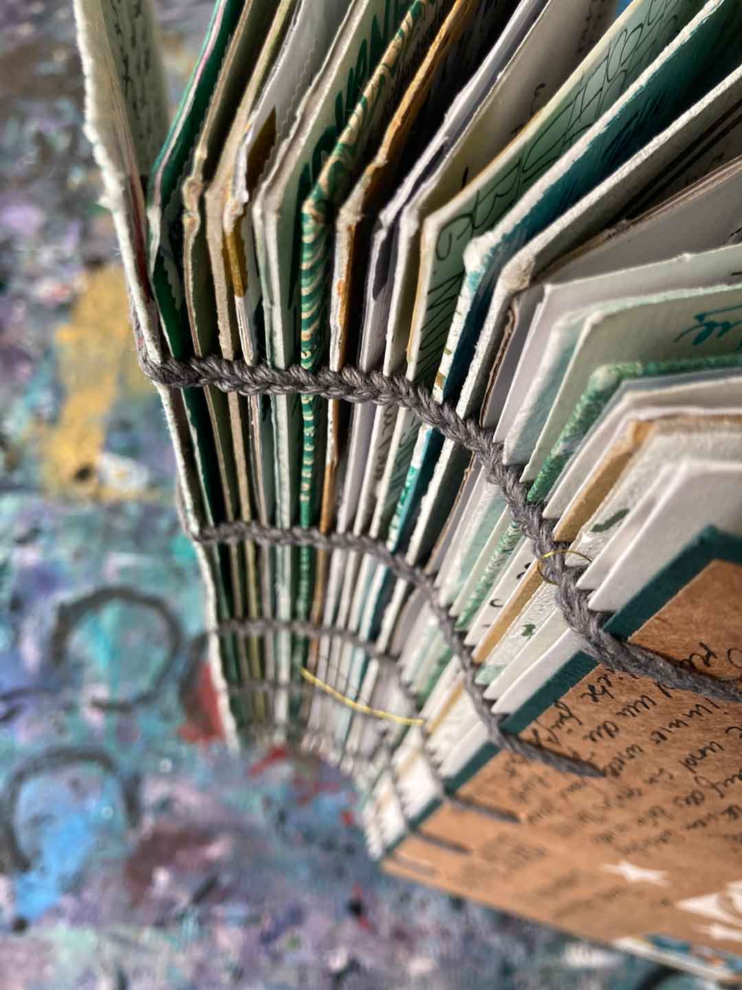 Der Waldwälzer, bestehend aus vielen Karten der Adventspost 2023, steht auf dem Tisch. Der Buchrücken ist offen und die bunten, unterschiedlich dicken Pappen der Karten ist zu erkennen.