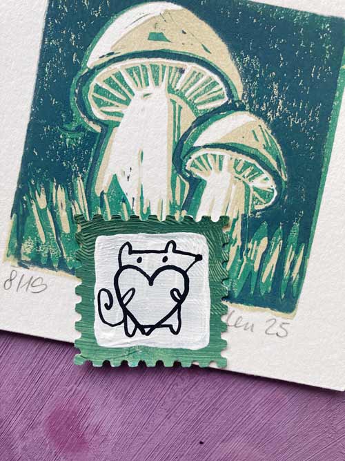 Mausita liegt unter den Pilzen von Michaela und hält ein großes Herz in den Armen.