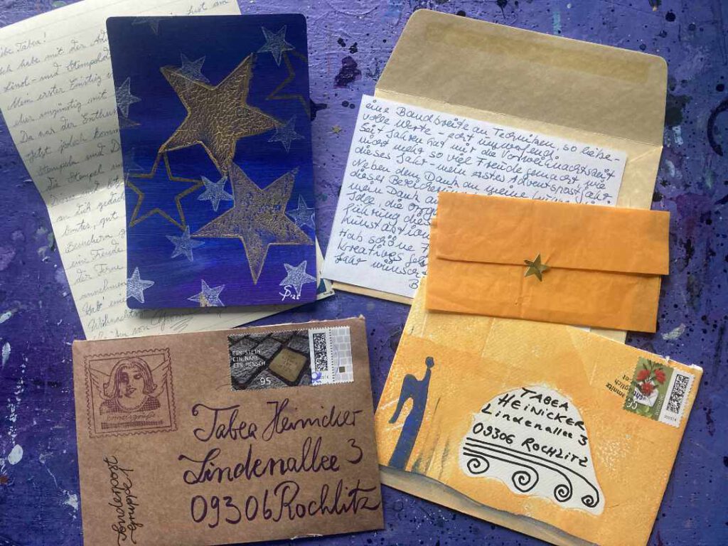 Besonders schöne Post! Die Adventspost war wieder sehr schön gestaltet. Briefumschläge in schönen Farben liegen neben handschriftlichen Karten und schönen Drucken und Papieren auf Tabeas Lila Arbeitsplatte.